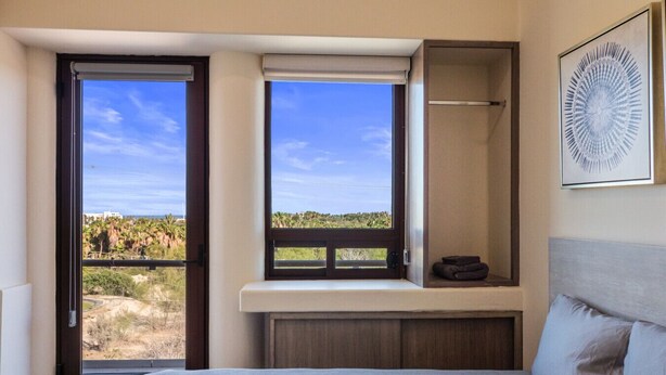 Un dormitorio con cama, ventana con vistas al paisaje y una obra de arte enmarcada en la pared.