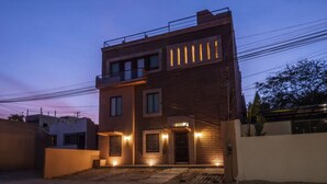 Un edificio moderno de dos pisos con techo plano, ventanas amplias y un balcón.