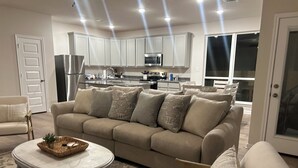 A living room with a beige sofa, a round coffee table, and a patterned rug.