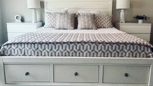 A neatly made bed with a patterned bedspread and two nightstands with lamps and decorative items.