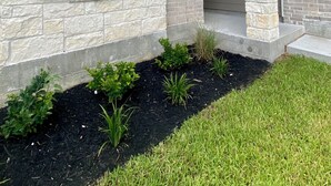 A house with stone exterior walls, a front porch, and a landscaped garden.