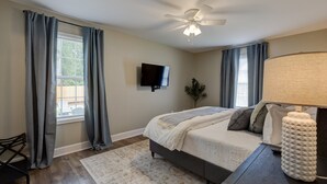 Une chambre à coucher avec un lit, un ventilateur de plafond, une télévision et une lampe.