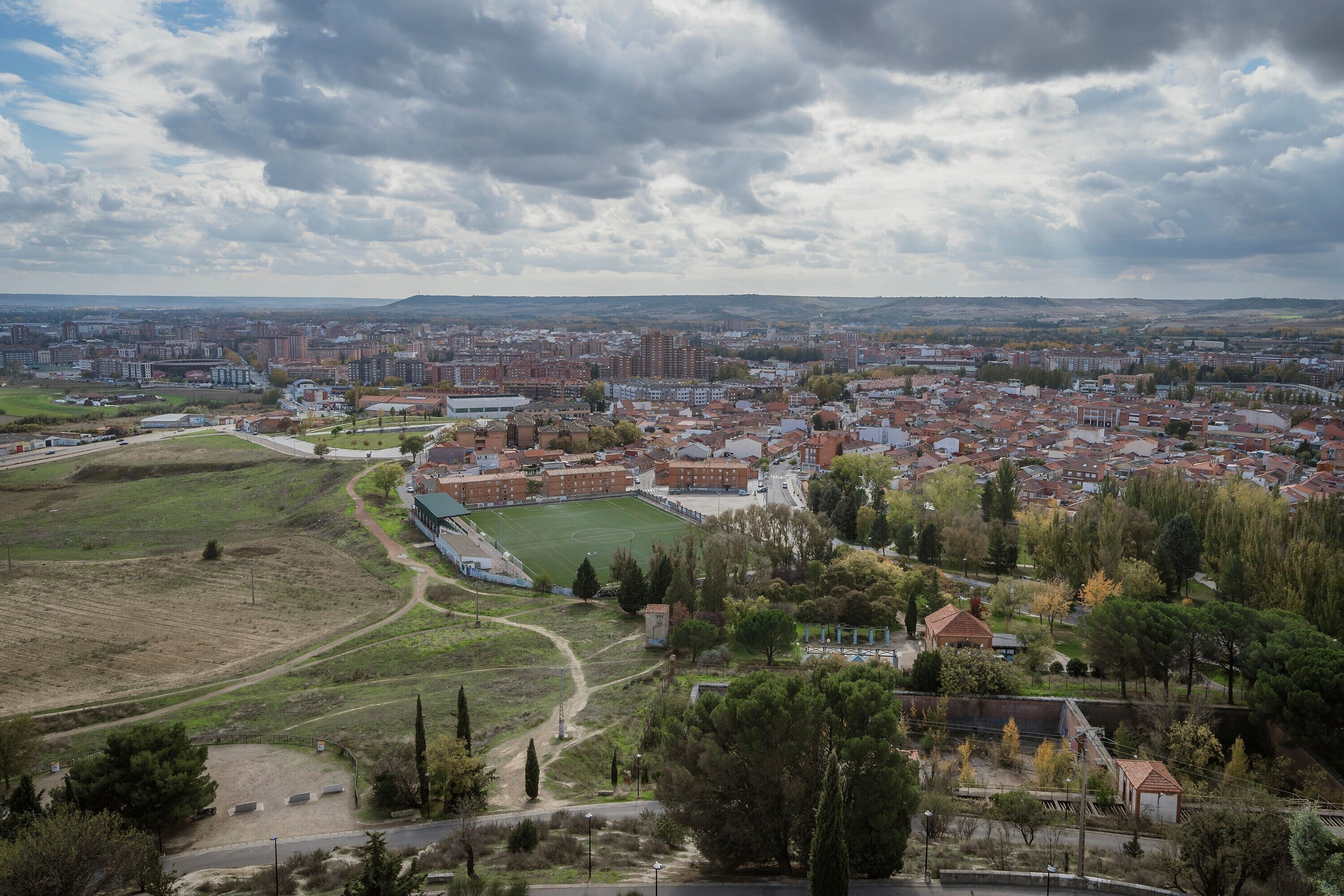 Un paisaje urbano con edificios residenciales, un campo deportivo y una zona de parque.
