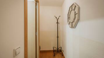 A hallway with a coat rack, a light switch, and a decorative wall piece.