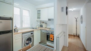 A compact kitchen with a washing machine, oven, and a small dining area.