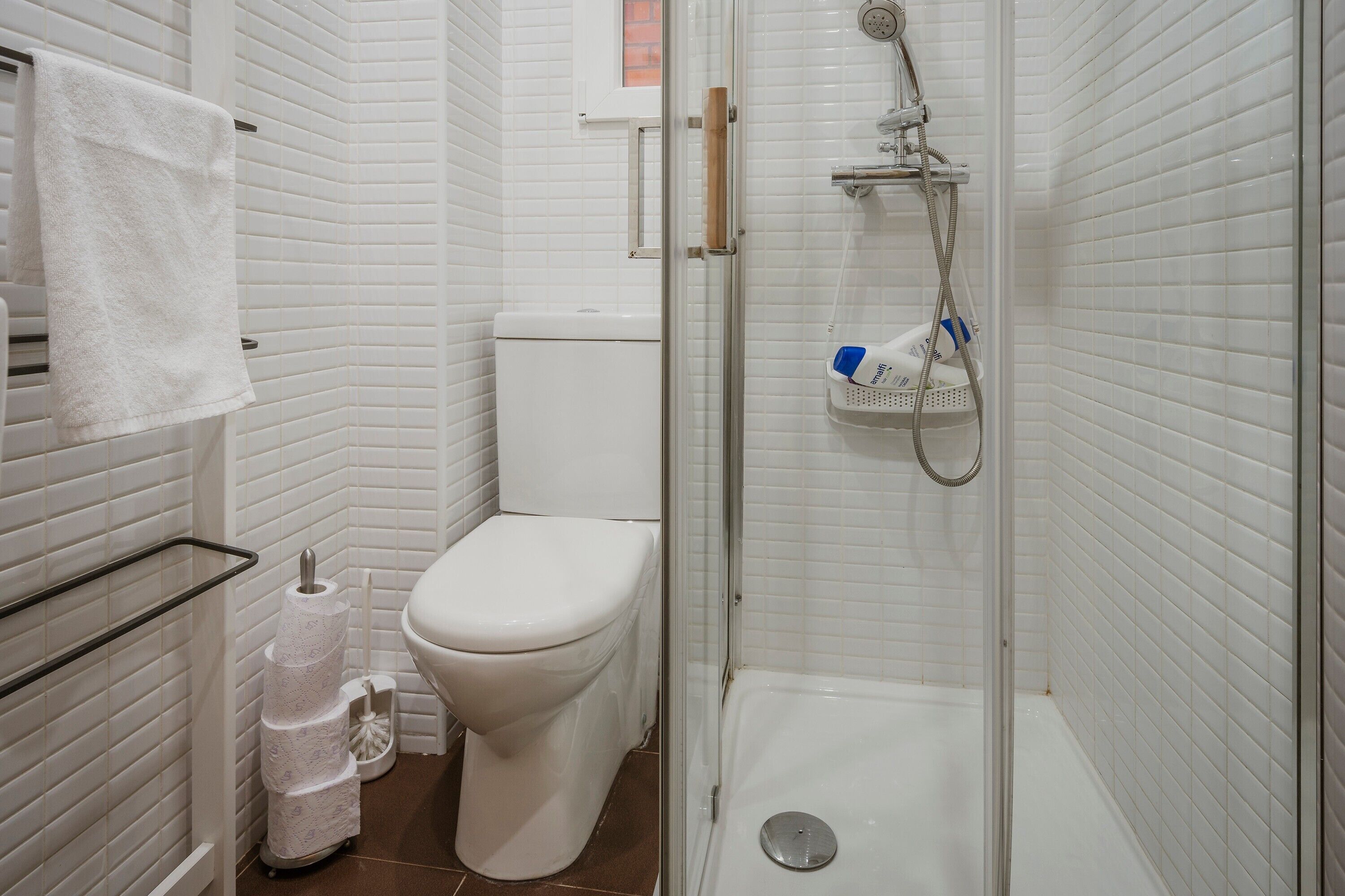 Un baño con inodoro, ducha y toallero.