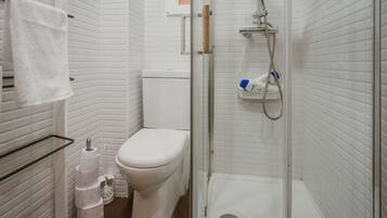 Un baño con inodoro, ducha y toallero.