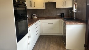 A compact kitchen with white cabinets, a built-in oven, a coffee maker, and a sink.