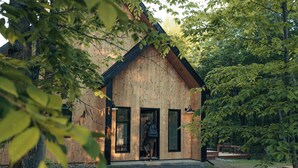 A wooden cabin with a porch, large windows, and a bench. - Cabine Origine  (Lac-Supérieur)