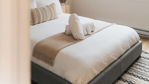 Et soveværelse med seng, et vindue og et trælofts.