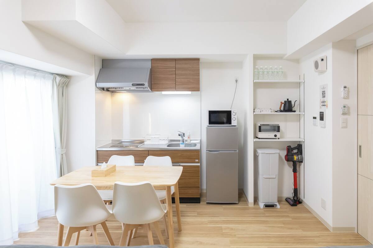Une cuisine compacte avec un coin repas, équipée d’un four à micro-ondes, d’un réfrigérateur et d’un aspirateur.