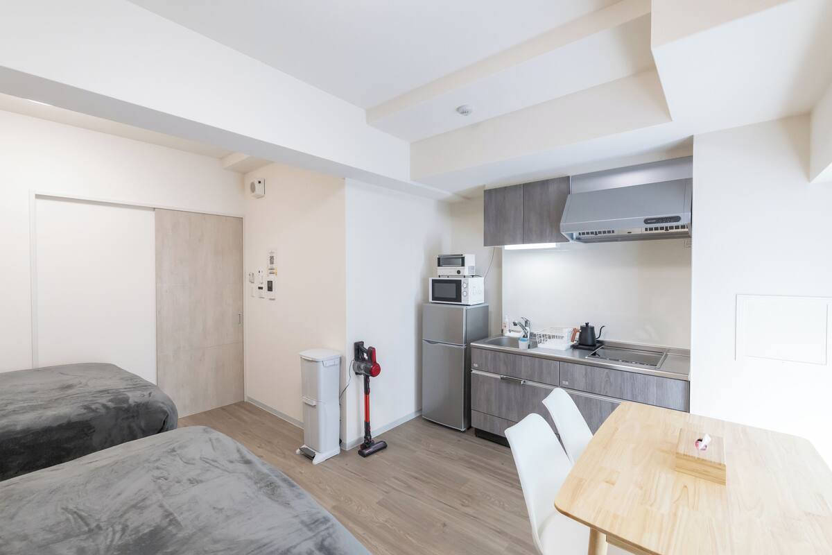 Une pièce de taille modeste comprenant un coin cuisine, un lit et une petite table.