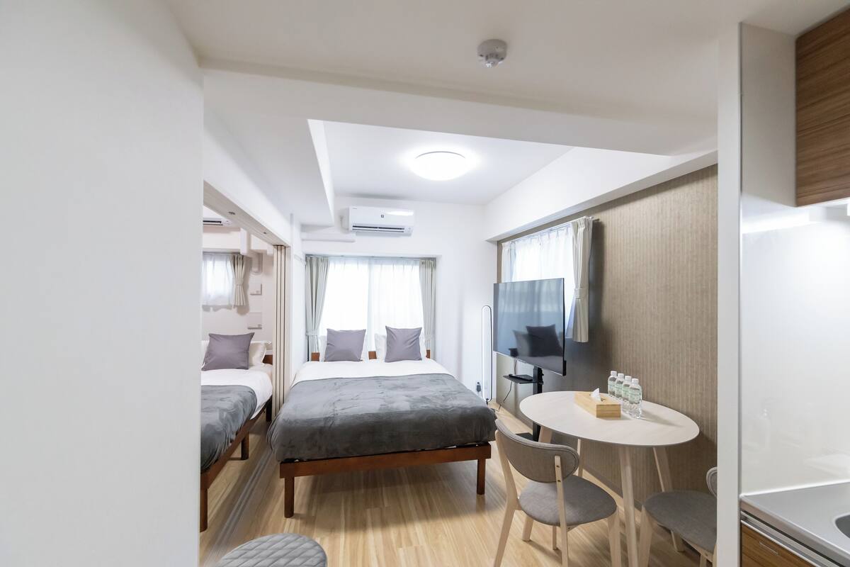 Une chambre d’hôtel comprenant un lit, une petite table avec des chaises, un téléviseur et un appareil de climatisation.