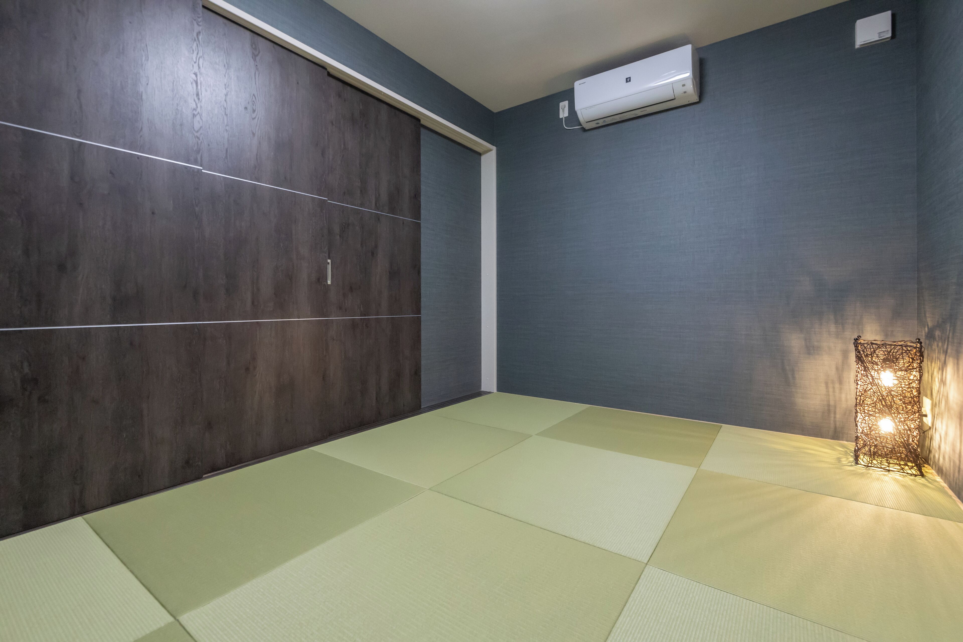 A room with tatami mats, a sliding door, and an air conditioning unit.