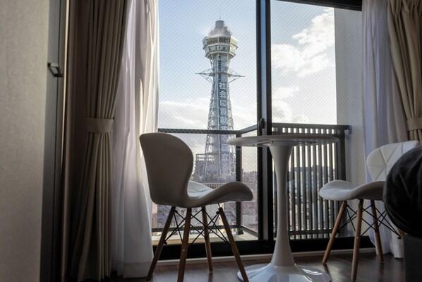 Un balcón con dos sillas y una mesa, con vista a una torre con texto en japonés.