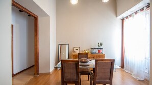 Ein Essbereich mit Holztisch und -stühlen, einem Holzschrank und einem Fenster mit leichtem Vorhang.