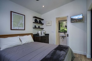 A bedroom with a bed, a map on the wall, a TV, and a door leading to a balcony.