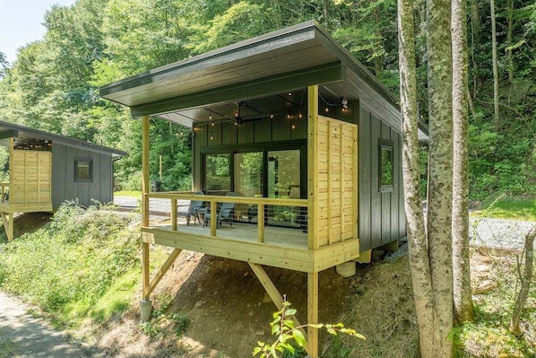 Eine Hütte mit einer Veranda, großen Fenstern und einer überdachten Terrasse.