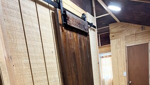 A room with a wooden sliding door, a light switch, and a wooden floor. - Cozy cabin in charming Ponca City with WiFi, AC (Ponca City)