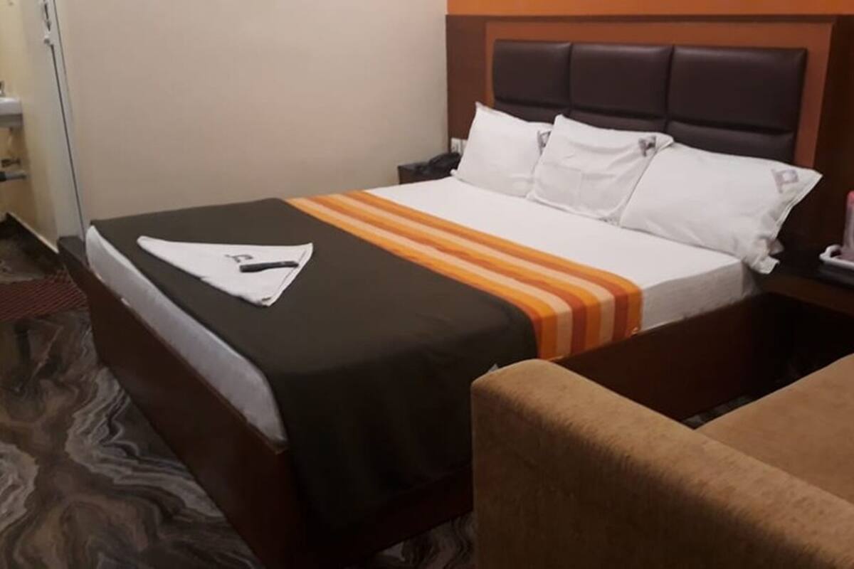 A hotel room with a bed, a nightstand, a chair, and a bathroom.