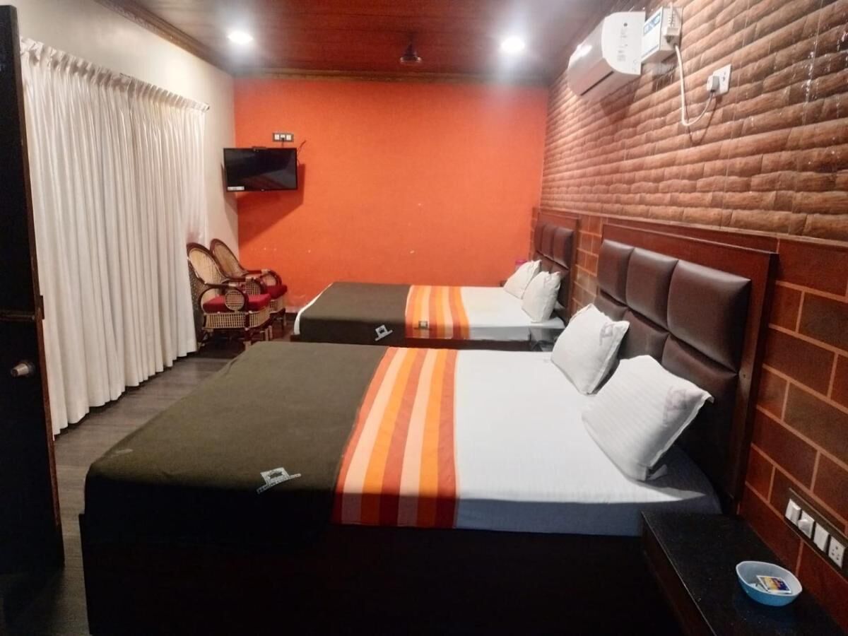 A hotel room with two beds, a television, and a brick wall.