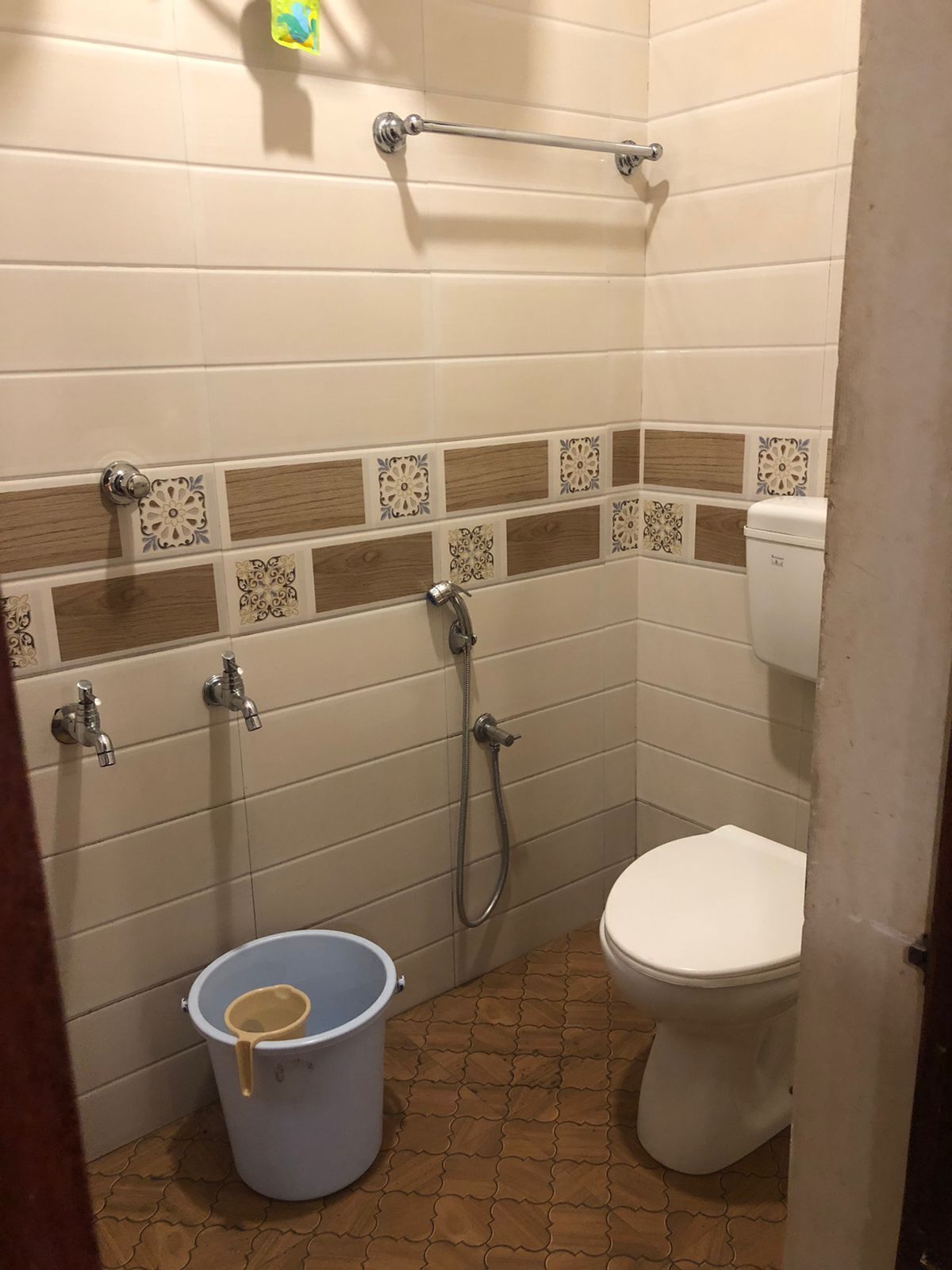 A bathroom with a toilet, a shower, and a bucket.