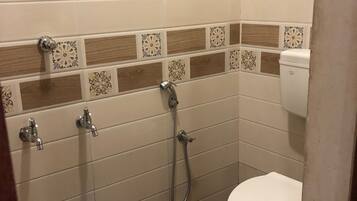 A bathroom with a toilet, a shower, and a bucket.