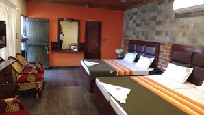 A hotel room with two beds, a sitting area with chairs, a mirror, and a stone wall. - FERDIN COTTAGE (Nagercoil)