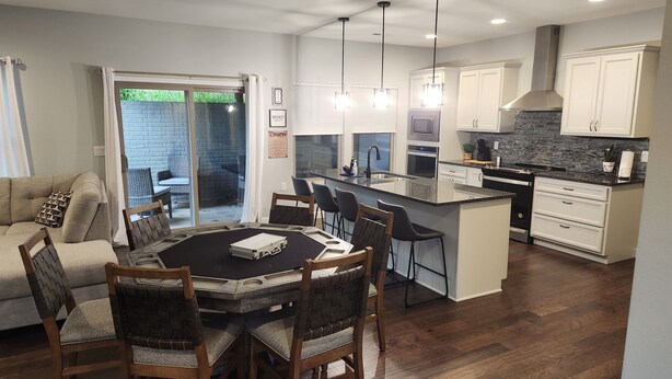 A modern kitchen with white cabinets, a central island, and a dining area with a black table and wooden chairs. - 3-bedroom house located near Camdenton. Nestled In Old Kinderhook community.  (Camdenton)