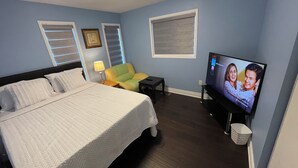 Een hotelkamer met een bed, een televisie, een stoel en een klein tafeltje.