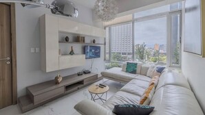 Ein modernes Wohnzimmer mit einer Couch, einem Fernseher und Dekoration auf einer Wandeinheit.