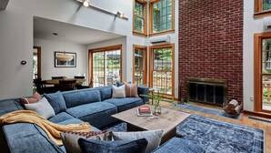A spacious living room with a large blue sectional sofa, a fireplace, and multiple windows providing natural light. - Perfect Nature Haven In Great Barrington (Great Barrington)