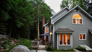 A two-story house with a deck, a chimney, and a large rock in the yard. - Perfect Nature Haven In Great Barrington (Great Barrington)