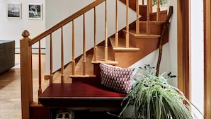 A wooden staircase with a red carpet, a chandelier, and a large plant. - Perfect Nature Haven In Great Barrington (Great Barrington)
