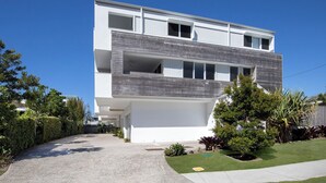 Una casa moderna de dos pisos con techo plano, ventanas amplias y un porche delantero cubierto.