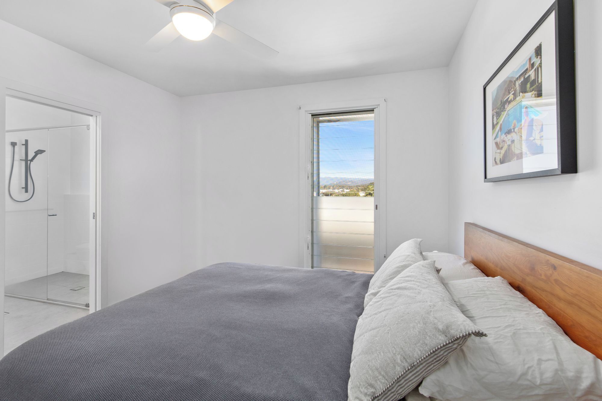 A bedroom with a bed, a shower, and a balcony.
