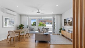 Amplia sala de estar con mesa de comedor, sofá y vista al exterior.