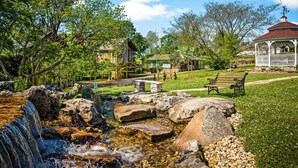 A park with a waterfall, picnic area, gazebo, and rustic buildings. - Fairway Treehouses (Berryville)