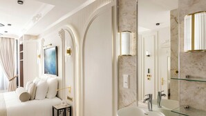 A modern bedroom with a large bed, a bedside table, and a nightstand. There is a large mirror with a marble backsplash and a built-in sink. - Merveil - Signature Suite -Tour Eiffel- Grenelle I (Paris)