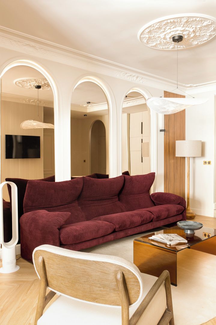 A modern living room with a red sofa, a wooden chair, a glass coffee table, and a lamp.