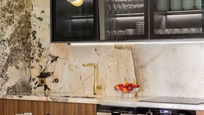 A modern kitchen with marble countertops, a built-in oven, and a dining area with wooden chairs and a marble table. - Merveil - Signature Suite -Tour Eiffel-Grenelle II (Paris)