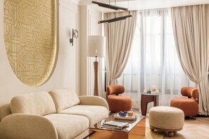 A modern living room with a beige sofa, two armchairs, a coffee table, and a floor lamp.