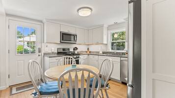 A modern kitchen with white cabinets, a microwave, stove, and a dining area with a round table and chairs.