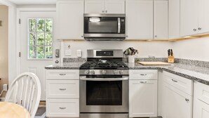 A modern kitchen with white cabinetry, a stainless steel stove, a microwave, and a built-in oven. - Cape Cod Cottage Near Beaches & Bike Trail (Harwich)
