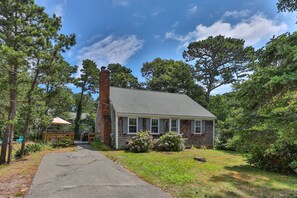 A two-story house with a brick chimney, surrounded by trees and a paved driveway. - Cape Cod Cottage Near Beaches & Bike Trail (Harwich)