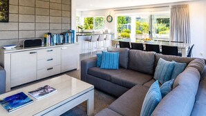 A modern living room with a sofa, coffee table, and a kitchen area with a dining table.