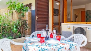 An outdoor dining area with a table set for four, surrounded by a bamboo fence and a wooden door. - Twin House - Le Lecce (Capoliveri)