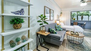 A modern living room with a grey sofa, a round coffee table, and a bookshelf with decorative items. - Waiakea Villas Gem. Shared Pool & Private Balcony!
 (Hilo)