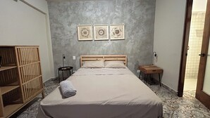 Un dormitorio con una cama, un armario de madera, una mesita de noche con lámpara y tres obras de arte colgadas en la pared.