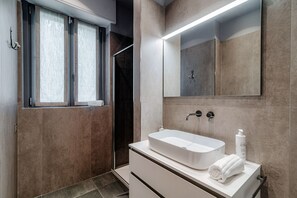 A modern bathroom with a large mirror, a white sink, and a towel on the counter. - Home Three Colors - MyHomeinComo (Como)